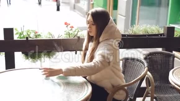 当咖啡蒸4K时漂亮的女孩摸着杯子在咖啡馆里用电话视频的预览图