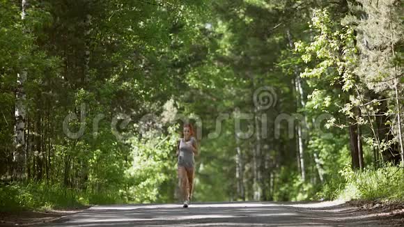 年轻的红发女孩穿过森林美丽的女孩去参加运动并监测健康慢动作视频的预览图