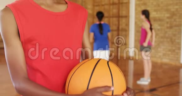 微笑的男孩拿着篮球而球队在后台比赛视频的预览图
