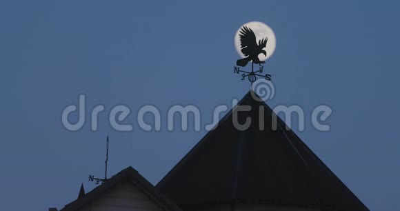 月亮在夜空中飞过建筑物的屋顶视频的预览图
