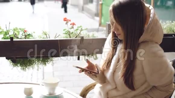 当咖啡蒸4K时在咖啡馆里用电话接近漂亮女孩视频的预览图