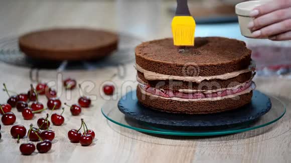 用樱桃准备巧克力蛋糕蛋糕用甜糖浆浸湿视频的预览图