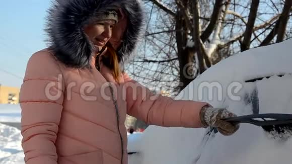 一个年轻女人从车里擦雪的冬天画像美丽的金发模特女孩笑着兴高采烈地打扫卫生视频的预览图