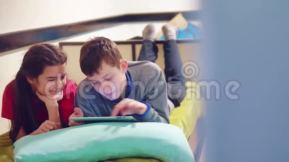 小男孩和小女孩在玩狗在平板上躺在床上青少年社会生活方式媒体视频的预览图