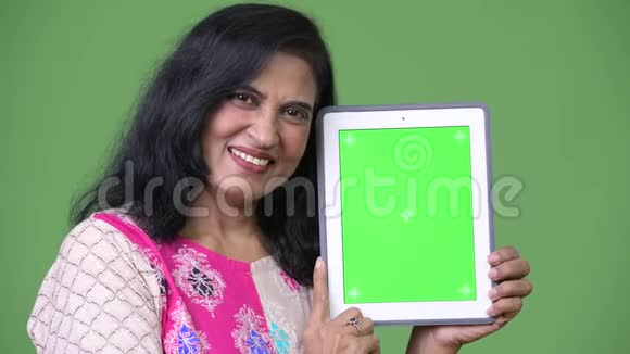 成熟快乐美丽的印度女人微笑着展示数码平板电脑视频的预览图
