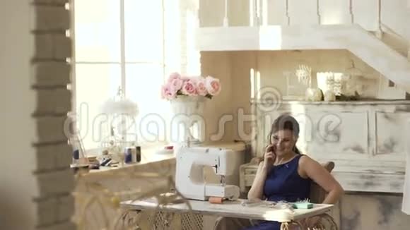年轻的服装设计师和缝纫工附近的女裁缝谈电话微笑工作室视频的预览图