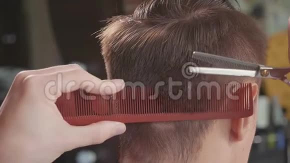 理发店里理发师的特写用剪刀缓慢地剪头发视频的预览图