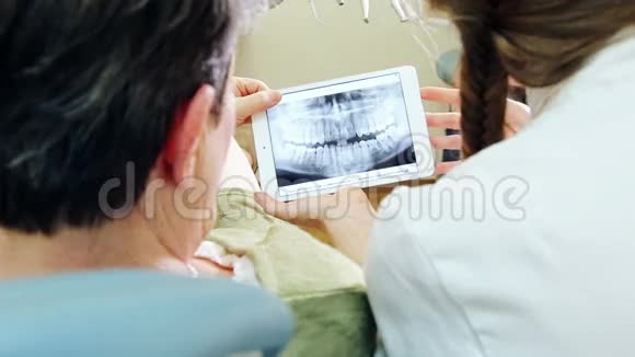 贴紧牙科医生的背面向病人展示X光牙齿视频的预览图