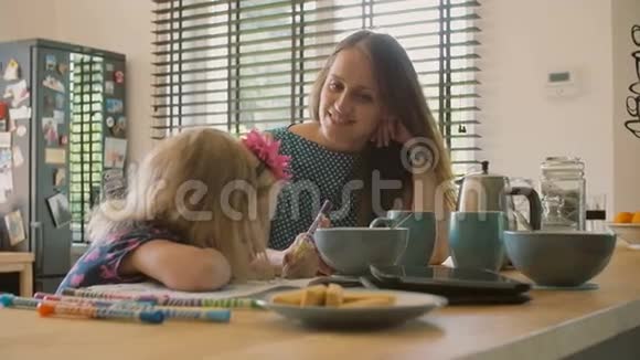 年轻快乐的母亲看着她可爱的金发女儿的颜色把她的头发从她的脸上刷下来慢动作视频的预览图