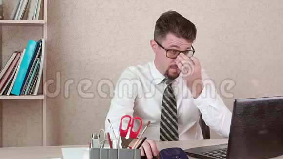 一个男人是一个办公室工作人员胡子和眼镜在笔记本电脑上工作视频的预览图
