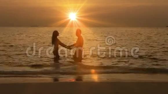 男人和女人的剪影日落时离开大海视频的预览图