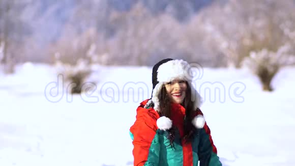 白雪皑皑的公园里的年轻快乐的女人那个女人用手拿着雪把它扔到空中一个女人视频的预览图