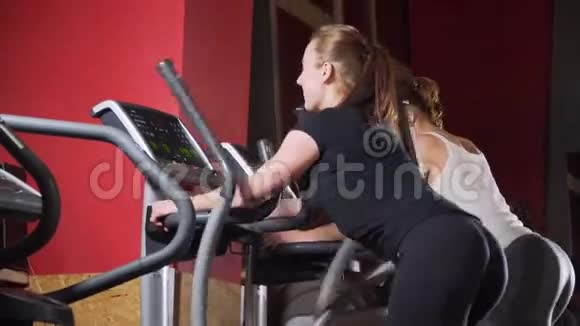 多民族人士在现代健身器材上健身在健身房运动漂亮的女人教练在玩视频的预览图