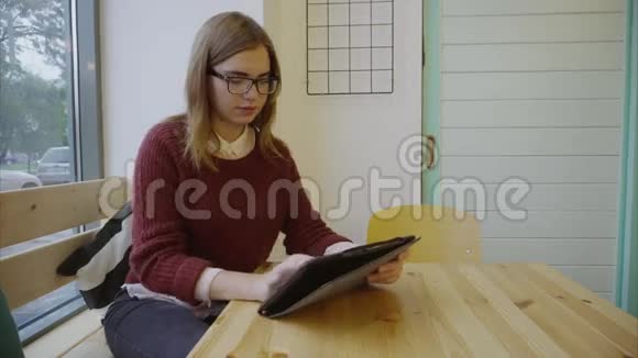 咖啡馆里带平板电脑的可爱女学生视频的预览图