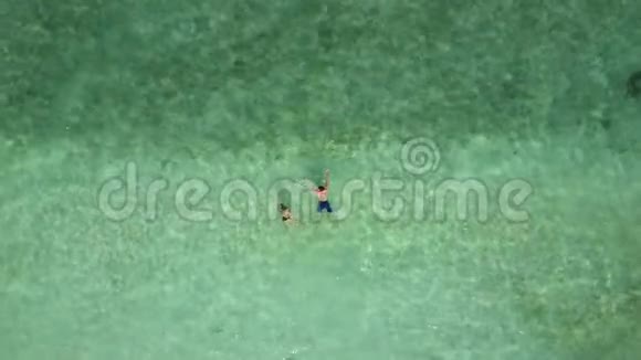 一对夫妇在印度洋的空海滩上游泳从上面可以看到两位恋人在蜜月中洗澡的空中镜头视频的预览图