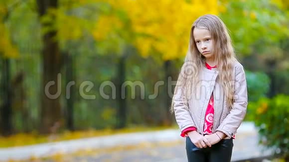 悲伤的小女孩在秋天看镜头和微笑的肖像视频的预览图
