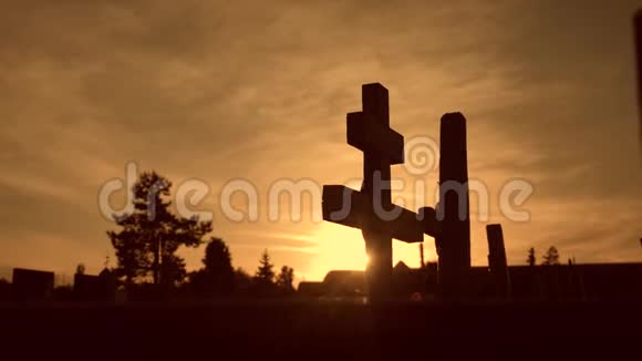 死亡生命的概念墓地在夕阳西下十字形剪影的生活方式中穿过从坟墓后面闪烁的阳光视频的预览图