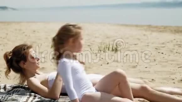 妈妈和女儿正在海滩上晒日光浴夏日晴天视频的预览图