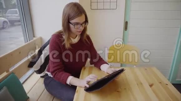 咖啡馆里带平板电脑的可爱女学生视频的预览图