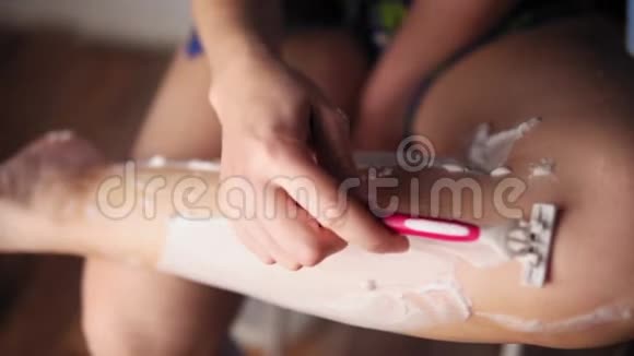 女孩在浴室里用剃刀把头发从腿上剃下来视频的预览图
