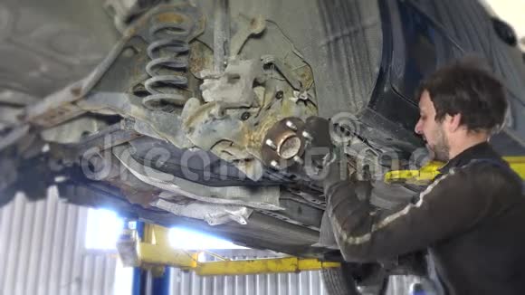 机械在汽车下面的车库中拆卸磨损的破碎汽车部件视频的预览图