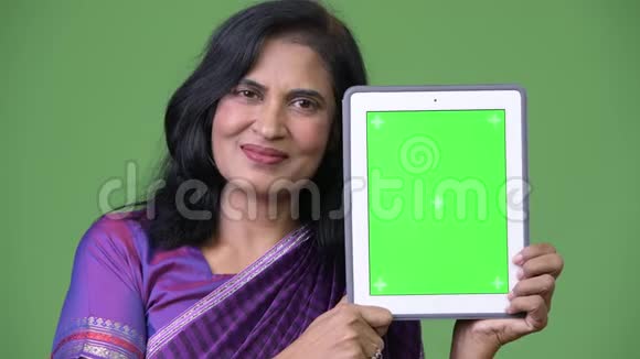 成熟快乐美丽的印度女人微笑着展示数码平板电脑视频的预览图