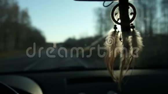 从车内后视镜上悬挂的捕梦器的视图开车旅行路和雪山的景色视频的预览图