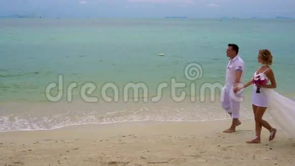 新娘和新郎沿着海滩散步视频的预览图