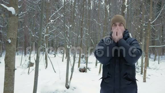 一个冬天森林结冰的年轻人他双手呼吸搓揉穿着罩衣冰雪景观他是视频的预览图