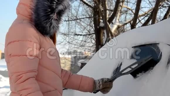 一个年轻女人从车里擦雪的冬天画像美丽的金发模特女孩笑着兴高采烈地打扫卫生视频的预览图