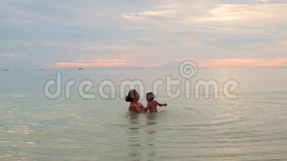 女孩和孩子在海里游泳和玩耍日落时间视频的预览图