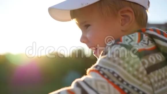 美丽的孩子看着相机在阳光的背景下微笑户外乐趣视频的预览图