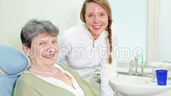 美丽的微笑牙医和年长的女人竖起大拇指视频的预览图