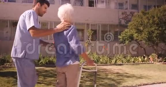 男护士协助一位年长妇女在花园散步视频的预览图