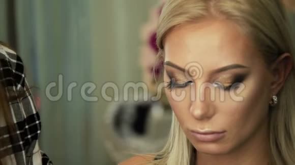 美容沙龙化妆师将睫毛贴在金色眼睛上视频的预览图