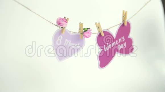 妇女节快乐妇女节纸上挂在一根绳子上靠近一颗粉红色的心上面装饰着鲜花背景白色视频的预览图