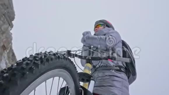 女人在冰上骑自行车女孩穿着银色羽绒服自行车背包和头盔女人是视频的预览图
