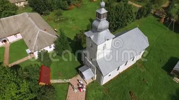 一座小教堂在村庄房屋和森林中的空中摄影视频的预览图