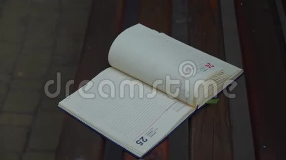 风把打开的笔记本书页变成了公园里的长椅商业理念视频的预览图