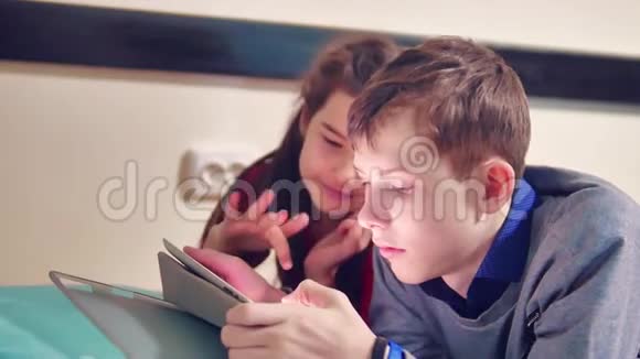 小男孩和小女孩在玩狗在平板上躺在床上青少年及青少年社交网站视频的预览图