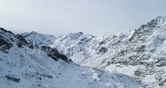 前方鸟瞰冬季雪山岩峰落基山脉的山顶覆盖着冰雪冰川视频的预览图