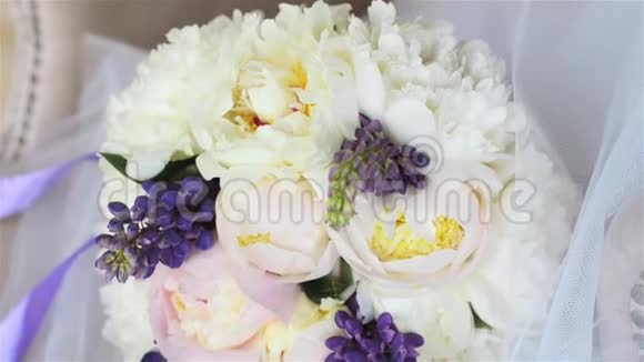 豪华照相馆白色扶手椅上的婚礼花束一束紫色丝带的牡丹和羽扇豆视频的预览图