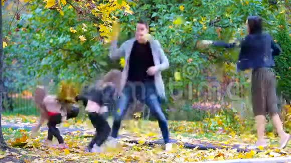 在秋天的户外活动中一家四口扔树叶的年轻人视频的预览图