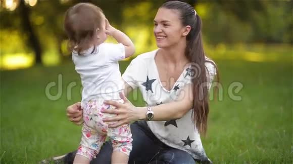 母女俩相爱相拥在公园玩耍小妈妈在花园里和孩子玩耍家庭幸福视频的预览图