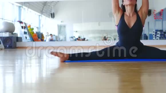 有长发的灵活女人在健身房的垫子上做运动视频的预览图
