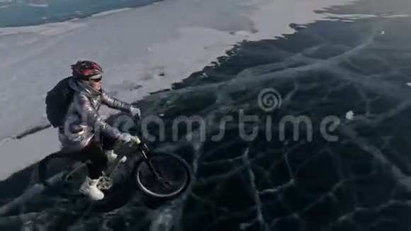 女人在冰上骑自行车女孩穿着银色羽绒服自行车背包和头盔射击视频的预览图