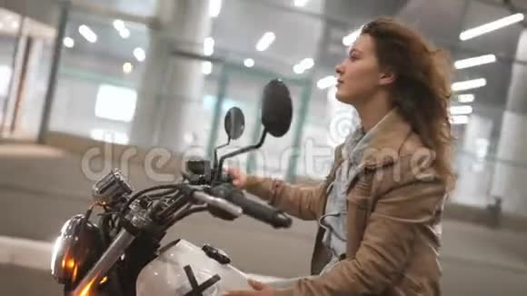 美丽的年轻女子骑着一辆古老的咖啡馆赛车摩托车在街上夜间道路上的女自行车手视频的预览图