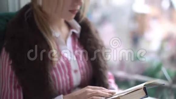 美丽的年轻女子坐在窗台上看书特写视频的预览图