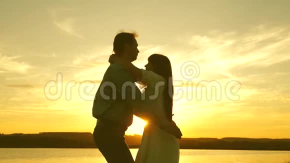 爱的男人和女人在湖底明亮的阳光下跳舞日落时分在海滩上跳舞的情侣快乐视频的预览图