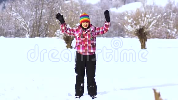 白雪皑皑的公园里的年轻快乐的女人那个女人用手拿着雪把它扔到空中一个女人视频的预览图